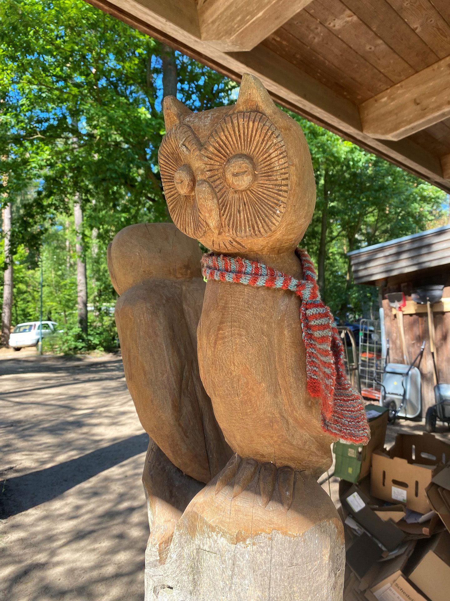 A carved wooden owl under a wooden roof.